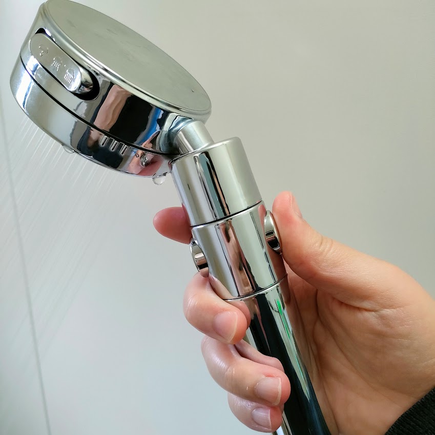 日丸屋製作所のシャワーヘッドの止水ボタンを押し込んで水圧の強さを調節する